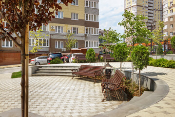 The benches in a courtyard near a new modern residential multi-storey building
