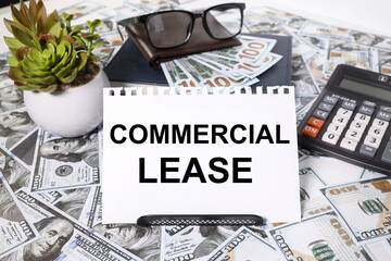 text COMMERCIAL LEASE. ON A WHITE BACKGROUND. WITH SCROLLED MONEY BILLS on the table, calculator, glasses, money purse and flower
