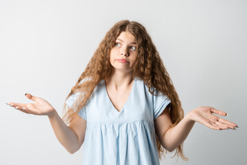 What wrong. Portrait of confused beautiful girl with curly long hair, spreads hands sideways,...