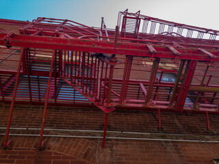 Fototapeta na wymiar red fire escape on brick building