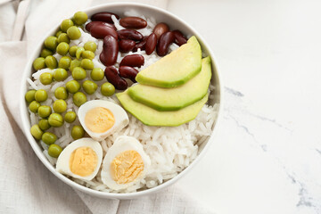 Bowl with tasty rice, beans, avocado and egg on table