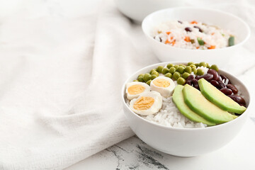 Bowl with tasty rice, beans, avocado and egg on table