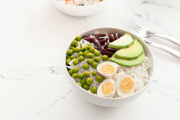 Bowl with tasty rice, beans, avocado and egg on table