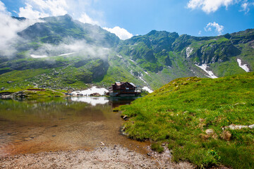 Fototapeta na wymiar clouds above balea lake in romania. stunning summer landscape in fagaras mountains. scenery reflecting in crystal clear water on a sunny day.