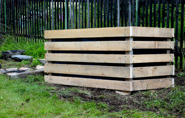 A composter made of natural beech prisms built horizontally with black foil inside in a meadow near...