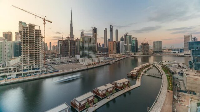 Small and luxury houses and skyscrapers near canal with clouds in the blue sky before sunset aerial timelapse in Business Bay, Dubai, United Arab Emirates