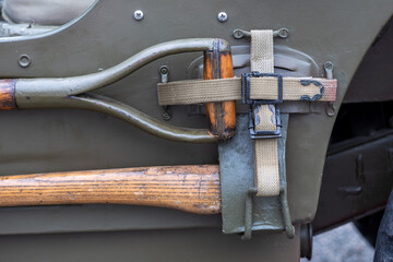 Detail of different work tools on the side of military vehicle. Shovel, Ax