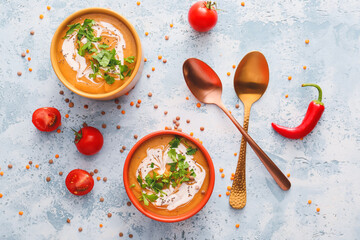 Bowls of tasty lentils soup on color background