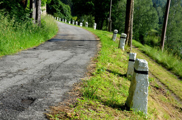 mountain road with traditional white stone bollards with a black stripe. Old stone pillars of...