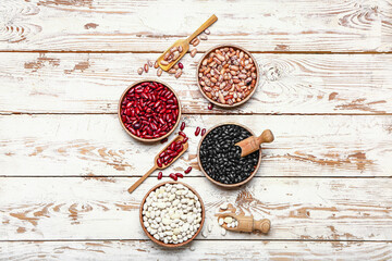 Different raw legumes on white wooden background