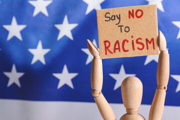 Mannequin with text SAY NO TO RACISM on poster near flag of USA