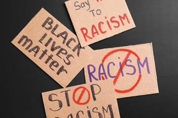 Different placards on dark background. Stop racism