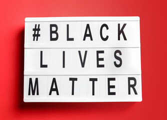 Board with hashtag BLACK LIVES MATTER on color background