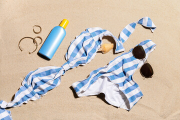 Beach accessories with sunscreen cream on sand