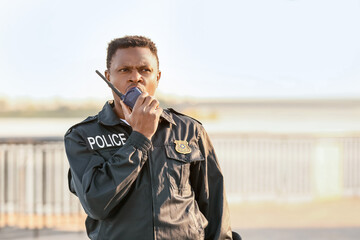 African-American police officer with two-way radio outdoors