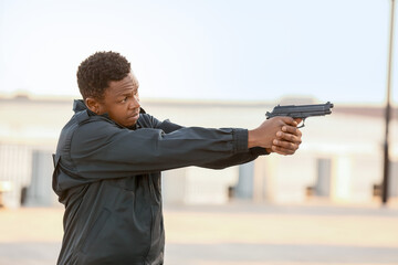 Aggressive African-American police officer with gun outdoors