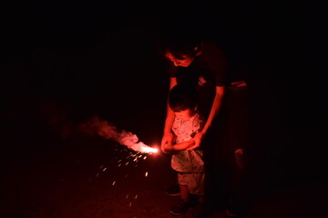 暗い中で手持ち花火をする3歳の男の子とパパ
