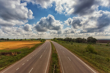 Fototapeta na wymiar Highway from the height of the bridge, against the background of clouds, fields and blue sky