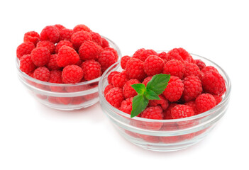 Raspberries and mint leaves in a glass bowls.