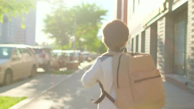 Schoolboy Little boy child with backpack alone going to school at sunset street outdoors. Back view. First-grade student, primary school, first grader, first class education, 4 K slow-mo