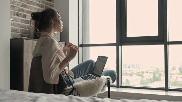 Young concentrated beautiful woman sitting indoors at home and using laptop computer