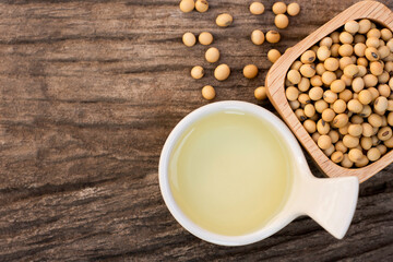 Soy bean oil with soybean seeds in   bowl isolated on rustic wood table background. Top view. Flat...