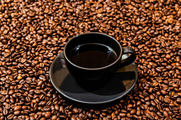 Black coffee mug on the coffee beans background