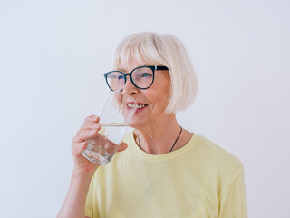 senior woman holding glass of water and drinking water. Healthy lifestyle, sport, anti age concept - Powered by Adobe