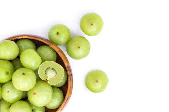 Close up  Indian gooseberry fruits ( Amla, phyllanthus emblica ) and cut i n half slice in wooden bowl isolated on white background. Top view. Flat lay.