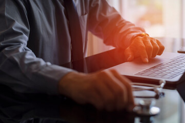 doctor man hands typing on laptop computer keyboard, search medical information with medical stethoscope on the desk at office. Online medical,medic tech, emr, ehr concept.