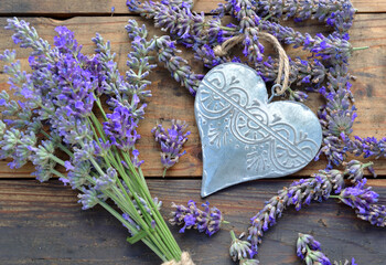 decorative metal heart among flowers of lavender on wooden background