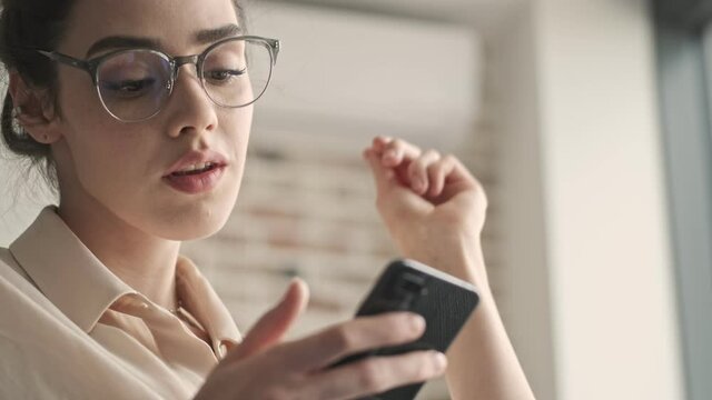 Young beautiful pretty woman sitting indoors at home and using mobile phone