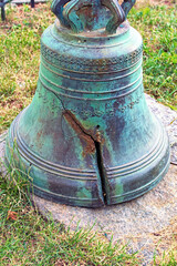 View of antique, cracked church bell on the cobblestone block. The bronze bell with fracture. Kyiv,...