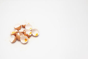 Eggshells with yellow and white powder symbolizing unhealthy food and mass production, white background