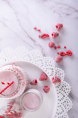 Milkshake in glass on white marble background decorated with iced raspberries