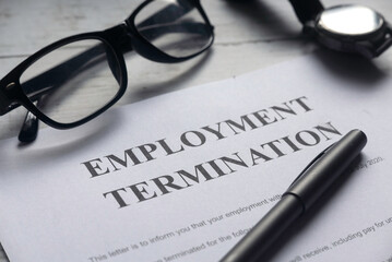 Selective focus of glasses,watch,pen and Employment Termination letter on a white wooden background.