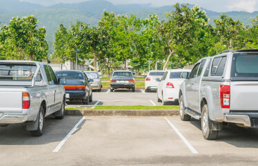 Fototapeta na wymiar Car parked in asphalt parking lot and one empty space parking in nature with trees and mountain background