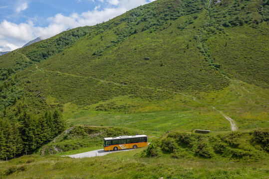 Glas Pass, SWITZERLAND - July 4, 2020: A typical Swiss Postal bus ("Postauto") crossing the road in the Piz Beverin National Park in Switzerland