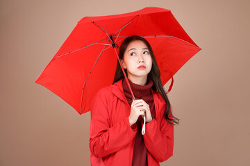 Asian woman with raincoat and umbrella outfit, Isolated mocha brown background