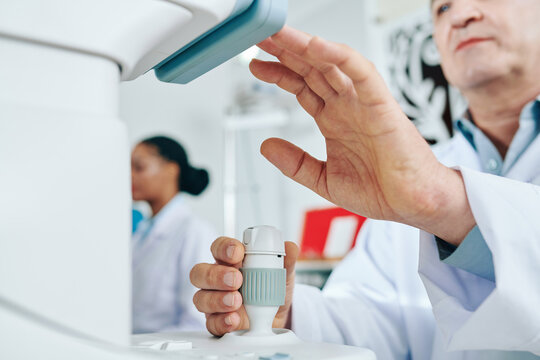 Close-up image of ophthalmologist using modern equipment when checking eyesight of patient
