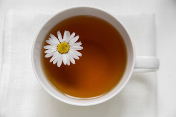 White cup with chamomile tea useful natural on a white background