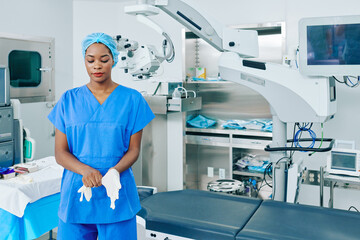 Obraz premium Young Black surgeon putting on rubber gloves when getting ready for surgery