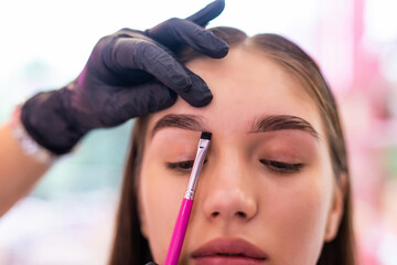 Permanent makeup for eyebrows. Beautiful woman with thick brows in beauty salon.