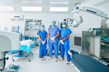 Serious confident surgeons in scrubs and medical masks standing in operating room