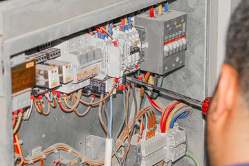 a professional electrician man is fixing the critical wiring connections of a electrical circiut board