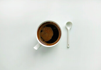 White cup of coffee and white ceramic spoon on a white background