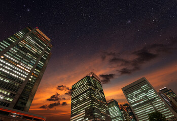 bottom view of skyscraper towers in a starry twilight sky, financial district and downtown office...