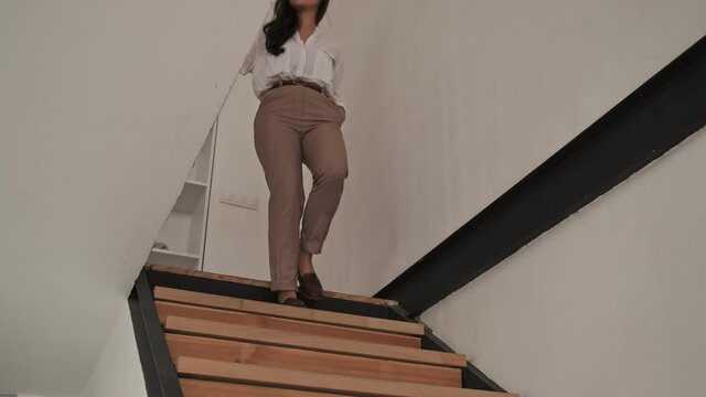 Happy elegant pretty asian woman walking on stairs with arm in pocket at home