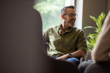 Mature businessman laughing during a meeting with office colleagues - obrazy, fototapety, plakaty