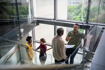 Foto op Plexiglas Diverse businesspeople talking on stairs in a modern office © JonoErasmus